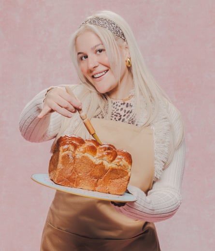 A blond woman holds a baked loaf of bread.