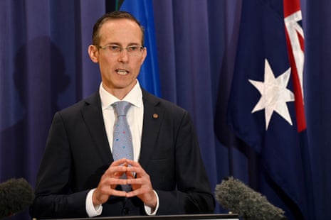 Andrew Leigh speaking to the media next to an Australian flag
