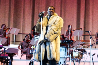 Giveon in a yellow fur coat performs on stage