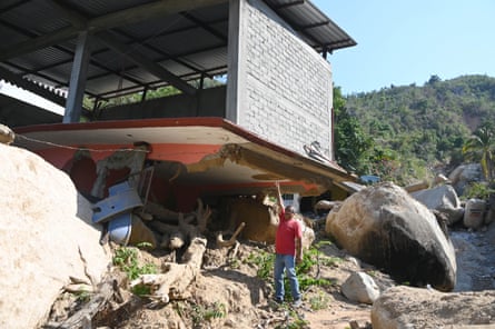 A man stands beneath a severely damaged building