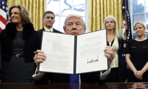 Donald Trump signs a presidential memorandum in the Oval Office, January 2017