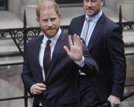 Prince Harry in a dark suit waving to people as he gets into his car
