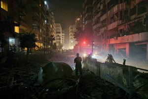 Emergency workers are seen amid damaged buildings and debris at night