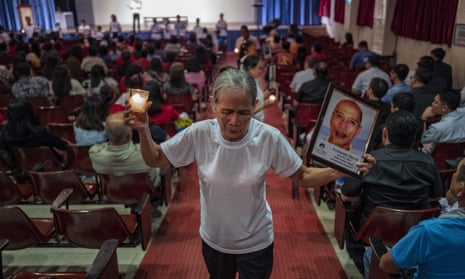 A woman, whose relative was killed in the drug war, shows a picture of her loved one to the audience