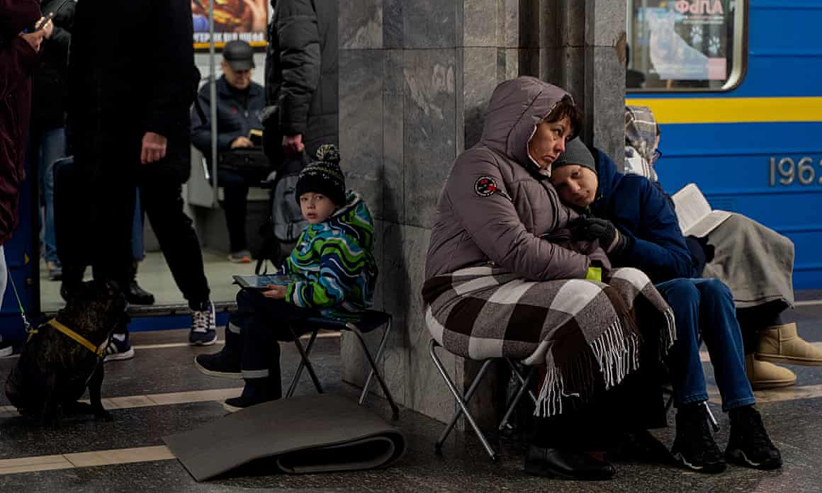 People sit on foldout stools and sit and stand on a subway train