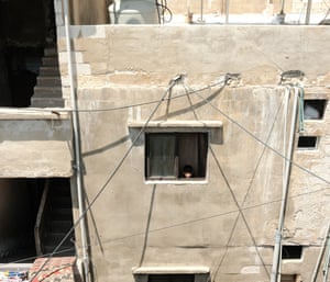 A boy looks out of a window on to Shatila’s  maze of streets. High-voltage cables are draped from buildings that are structurally unsound and frequently collapse