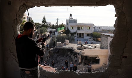 A man takes pictures of demolished houses in Hebron in the Israeli-occupied West Bank in 2023.