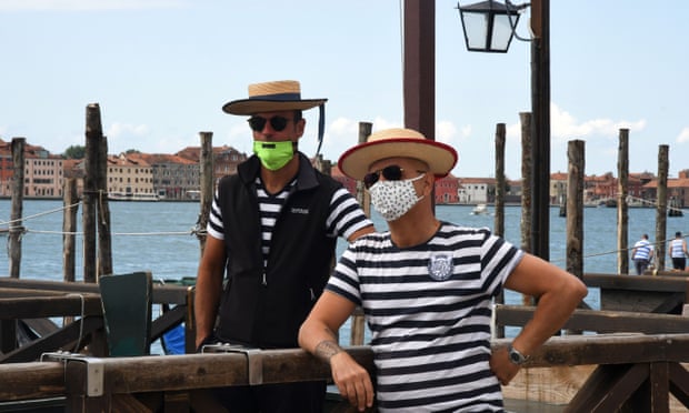 Gondoliers wearing protective face masks wait for tourists.