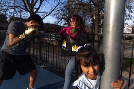 A woman and man boxing outside, a child in the foreground