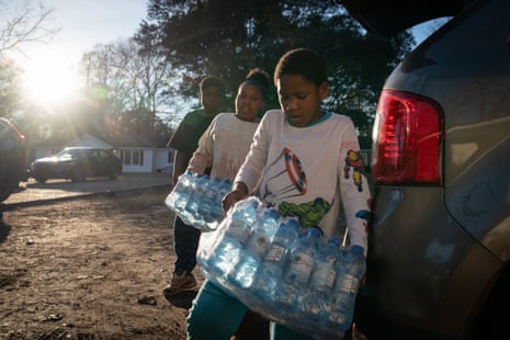 Three children carry cases of water bottles