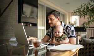 Man holding his newborn baby son and working with laptop at home