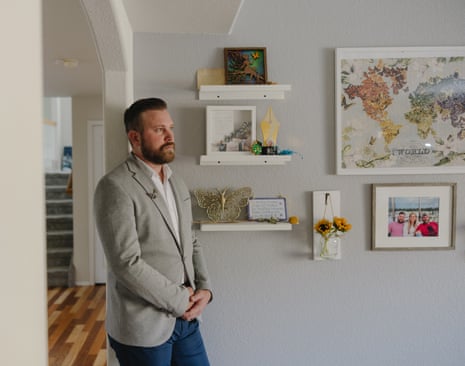 Sky Roberts leaning against a wall in a room in his house, with his hands clasped, looking to the left