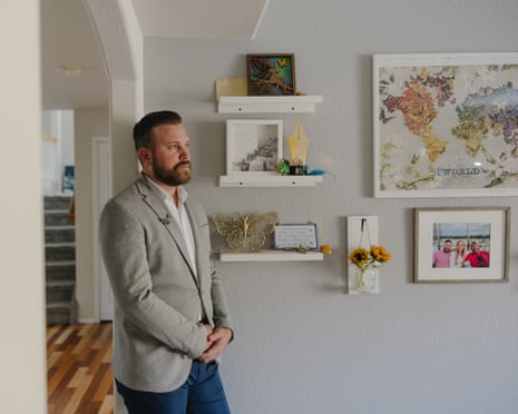 Sky Roberts leaning against a wall in a room in his house, with his hands clasped, looking to the left
