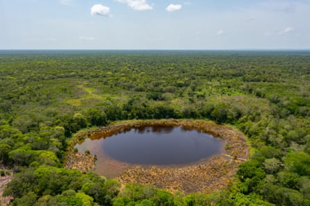 An aerial view of a pool of water in a tree-covered landscape