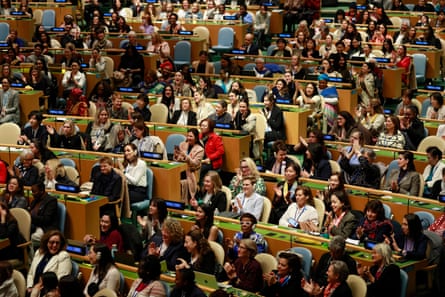 A crowded UN chamber with delegates seated in rows. behind desks.