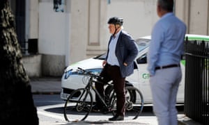 Conservative party leader Boris Johnson waits at a set of traffic lights on his bicycle in London.