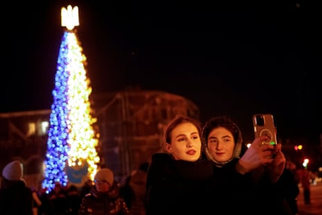 Women take a picture in front of a Christmas tree in Sofiiska Square in Kyiv.