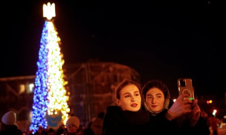 Women take a picture in front of a Christmas tree in  Sofiiska Square in Kyiv.