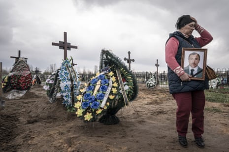 Natalia Maznychenko, 57, holds a portrait of her husband, Vasyl Maznychenko, 60, at a cemetery in Bucha.