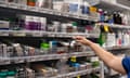 Hand reaching for bottles of medicine on a shelf