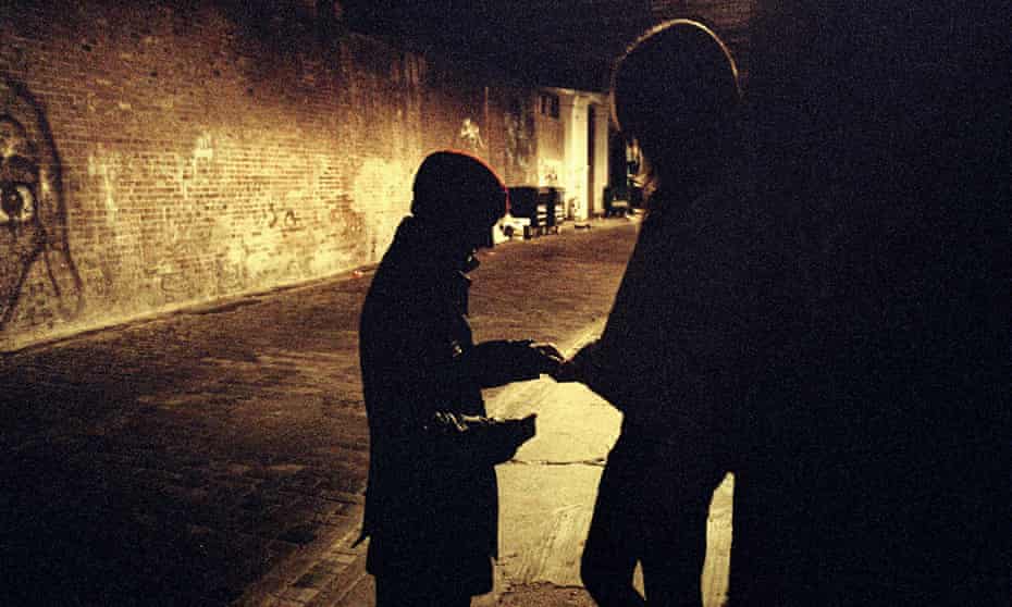 An exchange between a man and a woman on a dimly lit street.