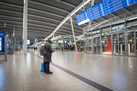 A lone passengers stands in the station’s hall looking up at departure screens