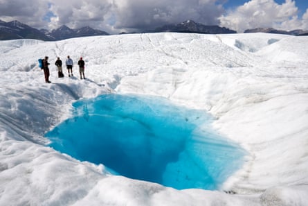 Hikers stand beside a pool on Root glacier at Wrangell-St Elias national park