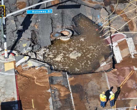 Aerial view of sinkhole, with two tiny men in neon yellow vests.