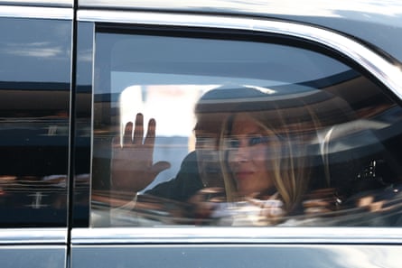 Donald and Melania Trump wave inside from a car