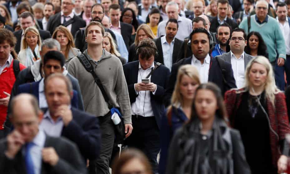 A commuter looks at his mobile phone as he crosses London Bridge during rush hour in London, Britain