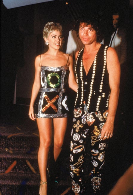 Kylie Minogue in a sequin noughts and crosses dress and Michael Hutchencei a black waistcoat with white buttons and black trousers with images of jewellery
