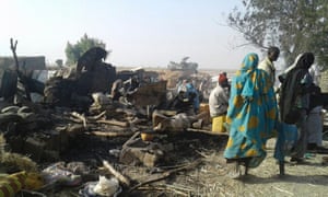 People stand next to site of bombing in Rann, northeast Nigeria