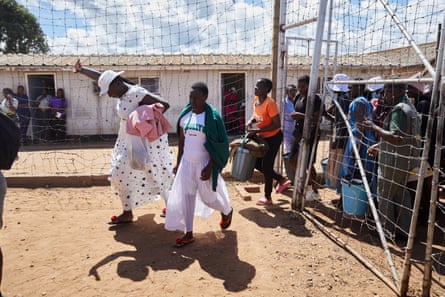 Two black women walk out of a prison gate, one raising her hand in the air, while a group of women behind the gates watch them.