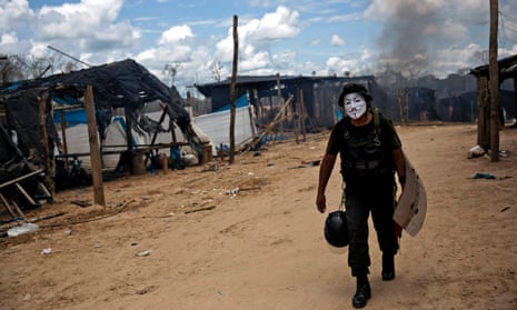 A police officer sports a Guy Fawkes mask he confiscated during continued government raids on illegal wildcat gold mining operations in La Pampa in 2016.