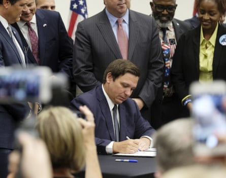 Ron DeSantis surrounded by people signing a bill.