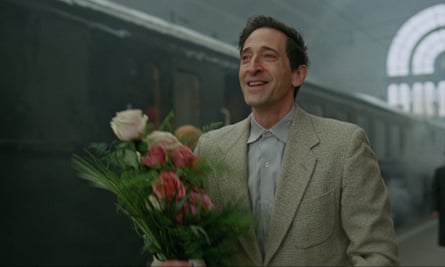 Adrien Brody carrying flowers at a railway station.