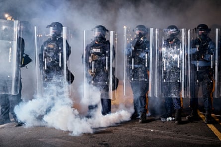 State police officers stand behind shields as tear gas fills the area outside the Delaney Hall detention center during a protest in Newark, New Jersey.