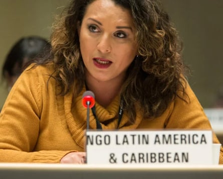 a woman speaking into a microphone with a sign in front of her