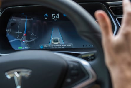 An image of a Tesla steering wheel and the dashboard, where the self-driving feature is shown.