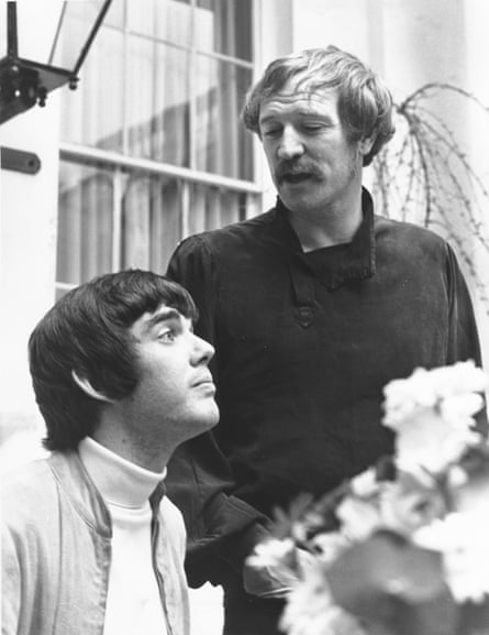 Webb sits while Richard Harris stands over him in a black and white shot.