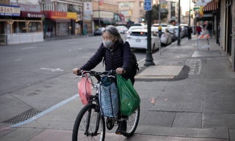 A woman rides a bike through Chinatown in Oakland, California.