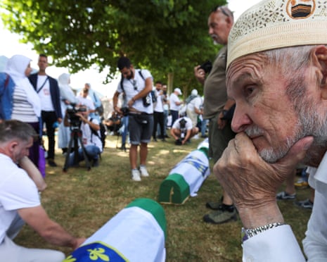A Bosnian Muslim man reacts near coffins during a mass funeral at the Srebrenica-Potocari Memorial Center in Potocari, near Srebrenica, Bosnia and Herzegovina.