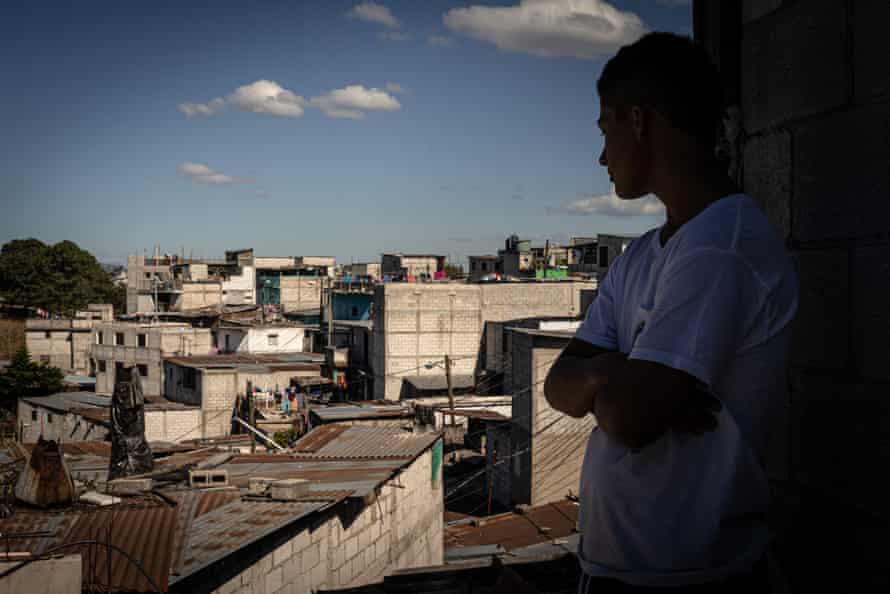 Boy is seen in sihouette observing his neighbourhood from a rooftop