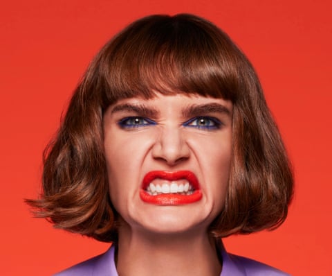Head shot of a woman pulling an angry face against red background