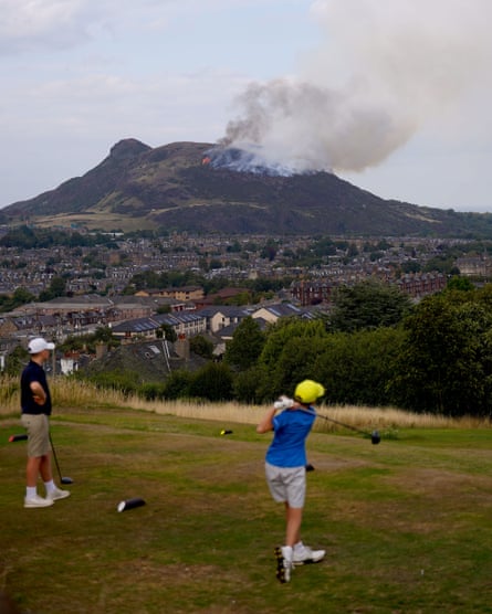 People playing golf with Arthur’s Seat on fire in the background