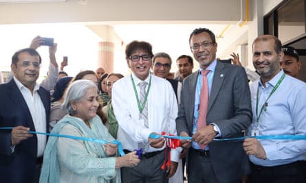 A crowd of smiling people behind a bright blue ribbon.