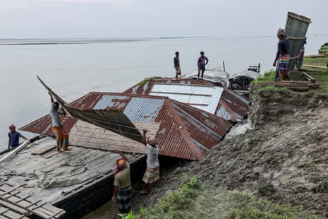 People carry parts of the house belonging to Nurun Nabi, 30, to load onto a boat, after he was forced to relocate to another island due to erosion caused by the Brahmaputra River, in Kurigram, Bangladesh