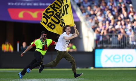 A pitch invader is chased by a security guard during the round 10 AFL match between Fremantle Dockers and Geelong Cats at Optus Stadium.