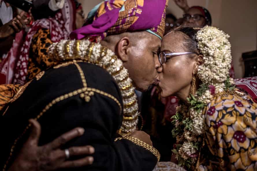 Surrounded by friends and family, the bride and groom share their first kiss at the bride’s home in Domoni