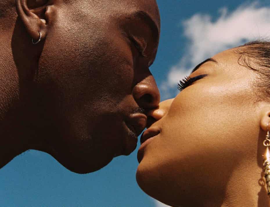 Head shot of couple Sean Cole (28) and Sophia Alonge (27) kissing against a blue sky background, May 2021